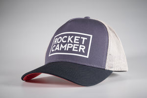 Klassische Truckercap in Blau mit weißem Mesheinsatz, großem "Rocket Camper" Logo-Print und roter Schildunterseite